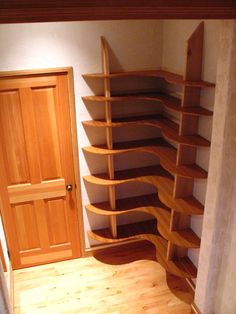 an empty room with wooden shelves in the corner and a door leading to another room