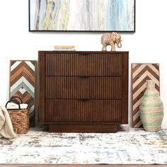 an elephant figurine sitting on top of a wooden dresser next to two baskets