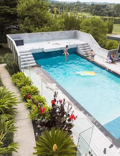 people are swimming in an outdoor pool surrounded by greenery