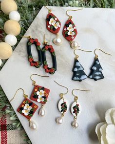 four pairs of earrings on top of a white table next to some flowers and eggs