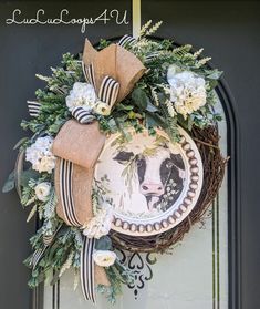 a wreath on the front door is adorned with an image of a cow and flowers