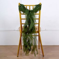 a yellow chair with a green scarf draped over it's back in front of a white wall