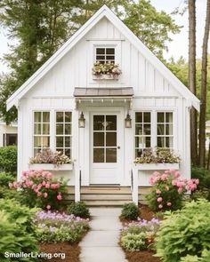 a small white house with flowers in the front yard