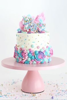 a white and pink cake with sprinkles on it sitting on top of a table