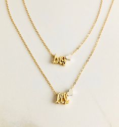 two gold necklaces with the word love written in cursive letters on them