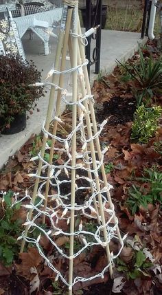 a tall wooden christmas tree sitting on top of leaves