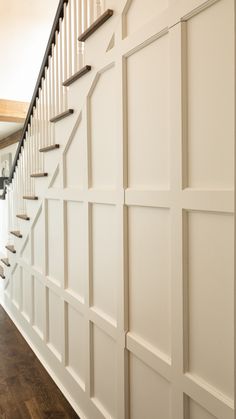 the stairs are lined with white paneling and black railings, along with wood flooring