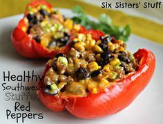 two stuffed red peppers on a plate with lettuce and black beans in them