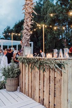 an outdoor bar is decorated with lights and greenery