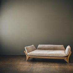 a white couch sitting on top of a wooden floor next to a gray wall in an empty room