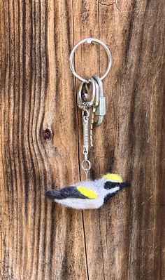 a bird keychain hanging on the side of a wooden wall