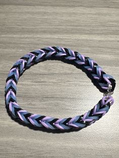 a purple and black braided bracelet sitting on top of a wooden table