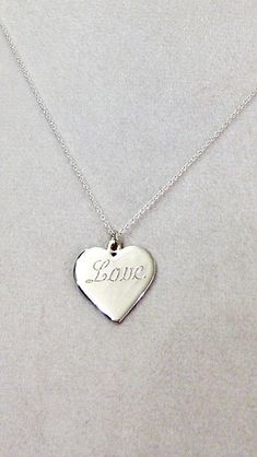 "Sterling Silver Heart Necklace with \"Love\" Engraved This makes for a perfect holiday gift or as a gift for your bridesmaids. This piece is made out of a solid, 925 sterling silver heart engraved with \"Love\" on a solid, 925 sterling silver chain available in 16\", 18\" or 20\" long. Heart measures roughly 3/4\" X 3/4\" (17.94 mm x 17.47mm) All of my jewelry is handmade. It is ARTISAN jewelry. It does not have the \"glass-like mirror finish\" like that of a fine jewelry store. The natural imperfections in the jewelry are what makes my jewelry uniquely beautiful and your item truly one of a kind.. Please do not expect the \"perfect\" look that you get when you purchase machine or cast made jewelry." Heart Pendant Necklace For Valentine's Day Wedding, Heart-shaped Wedding Necklace With Engraving Option, Heart Shaped Wedding Necklace With Engraving Option, Heart Pendant Necklace With Engraving Option For Wedding, Heart Pendant Necklace For Wedding On Valentine's Day, Heart-shaped Pendant Necklace For Wedding And Valentine's Day, Personalized Heart Pendant Necklace For Wedding, Personalized Pendant Heart Necklace For Wedding, Silver Heart Necklace For Valentine's Day Wedding