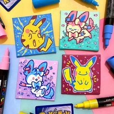 several different colored pokemon cards on a table with markers, pens and markers next to them