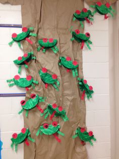 a paper bag with green and red frogs on it hanging from the side of a wall