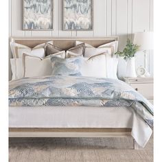 a bed with two paintings on the wall above it and an ocean themed comforter