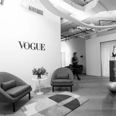 black and white photograph of an office with two chairs in front of a wall that says voque