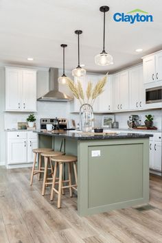 Modern kitchen with a large kitchen island with a green kitchen island with a black marble countertop, white cabinets surround the kitchen with silver handles, great granite countertops and a stainless steel range hood. Sage Kitchen Island Black Counter, Green Kitchen Island Black Counter, Colored Island With Black Countertop, Green Cabinet With White Countertop, Green Kitchen Island Pendant Lights, White Cabinets Accent Island, Black Countertops Island, Kitchen Green Island White Cabinets, Green Island With Black Countertop