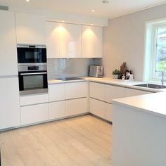 a modern kitchen with stainless steel appliances and wood flooring is pictured in this image