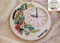 a white clock with flowers and leaves painted on the front is sitting on a blanket