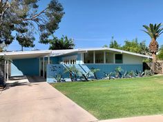 a blue and white house with palm trees in the back yard, on a sunny day