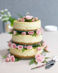 a three tiered cake with pink flowers on top and greenery around the edges