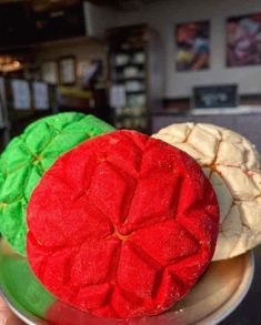 two red and one green cookies on a plate