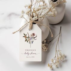 two white vases with flowers on them and a tag that says, virginia's baby shower