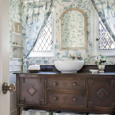 a bathroom with blue and white wallpaper, a sink and window in the corner