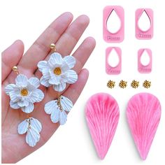 pink and white flowers are being held in front of two pairs of earring hooks