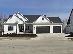 a large white house with black garage doors