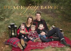 a family is sitting on a blanket in the grass with their two children and one adult