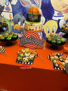 a table topped with cupcakes and cakes covered in frosting next to cartoon characters