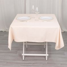 the table is set with two empty plates and wine glasses on it, ready to be served