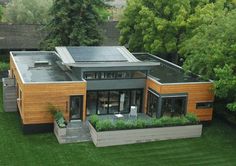 an aerial view of a modern house with solar panels on it's roof and landscaping