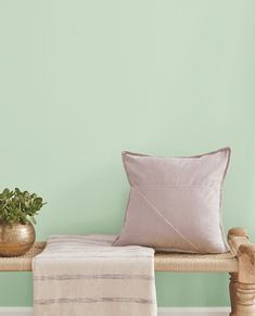 a wooden bench with two pillows and a potted plant