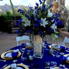 a table set with blue and white plates, silverware and flowers in a vase