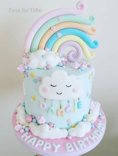 a birthday cake decorated with clouds, rainbows and stars