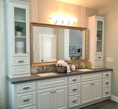 a bathroom with double sinks and large mirror over it's counter top, along with white cabinets