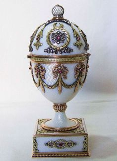 an ornate white and gold urn sitting on top of a table