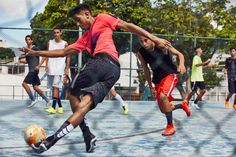 young men playing soccer on an outdoor court with trees in the backgrouds