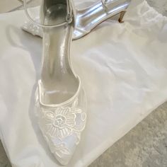 a pair of white wedding shoes sitting on top of a table next to a purse