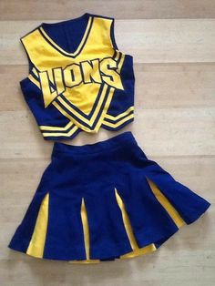 a blue and yellow cheerleader uniform is laying on the floor next to a pair of shoes