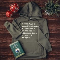 a book and sweatshirt sitting on top of a wooden table next to a plant with flowers