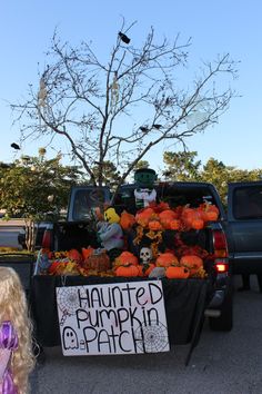 a truck with pumpkins and decorations in the back is parked next to a sign that says, haunted pumpkin patch