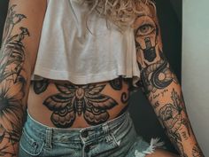 a woman with lots of tattoos on her stomach and arms is posing for the camera