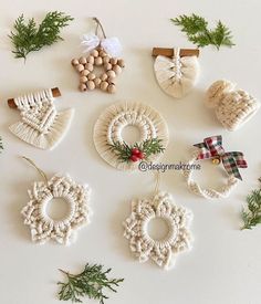 christmas ornaments are arranged on a white surface with pine needles and greenery around them