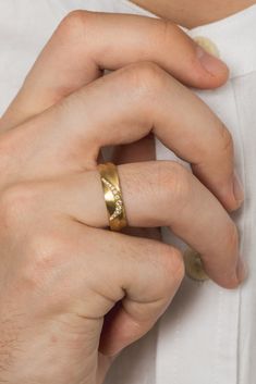 a man wearing a gold wedding band and white shirt