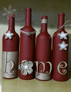 three red wine bottles decorated with flowers and monogrammed ribbons are sitting on a shelf