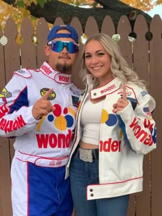 a man and woman posing for a photo in front of a fence with the word wonder written on it